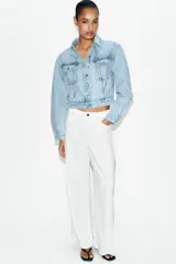 Cazadora corta de denim color celeste con cuello solapa, manga larga y hombreras. Cuenta con bolsillos delanteros con solapa y cierre frontal de botones metálicos.