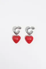 Aros tipo argolla plateada de metal con colgante en forma de corazón rojo brillante.