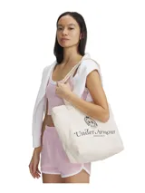 Bolso tipo tote de lona color beige, con diseño de logo Under Armour Athletics estampado en el frente. Cuenta con un amplio compartimento principal y correas dobles para llevar al hombro.