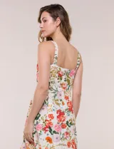 Vestido midi evasé de lino estampado con diseño floral multicolor sobre base beige. Cuenta con escote cuadrado, tirantes anchos y cierre invisible en la espalda.