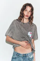 Camiseta oversize de algodón con efecto lavado en color gris, cuello redondo y manga corta. Presenta un estampado gráfico pequeño en el pecho con diseño de nube y cereza.
