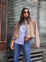 Campera bomber color beige, de corte oversize, con cuello redondo, cierre frontal de broches y mangas abullonadas.