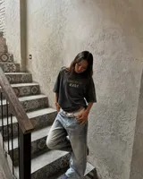 Remera marrón oversize con cuello redondo y mangas cortas. Estampado frontal con el texto "Uruguay Run Club" en celeste y siluetas blancas de personas corriendo.