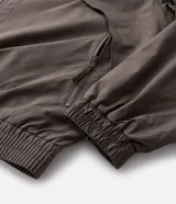 Campera rompeviento color verde militar, con cierre frontal de cremallera, cuello alto, puños y cintura elásticos. Presenta recortes delanteros y un pequeño logo estampado en el pecho.