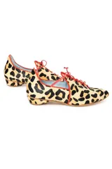 Zapatos tipo blucher de pelo de pony con estampado animal print. Presentan cierre de cordones rojos, ribetes de ante a contraste y una silueta geométrica con aberturas laterales. Cuentan con tacón forrado de 2 cm en forma de lágrima y suela de cuero.
