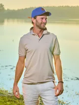 Remera tipo polo color beige, de corte clásico, con cuello y puños acanalados en contraste marrón oscuro.