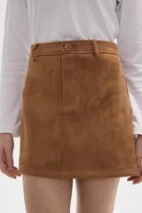 Falda mini de corte recto confeccionada en gamuza sintética color marrón, con cierre frontal de botón y presillas para cinturón.