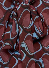 Camisa de manga larga con estampado abstracto en tonos borgoña y celeste. Tiene cuello redondo con lazo y cierre frontal con botones.