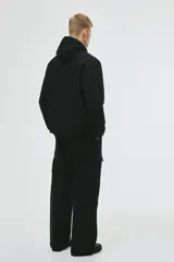 Campera rompevientos negra de nylon repelente al agua, con capucha ajustable, cierre frontal, bolsillos laterales y puños elásticos.