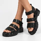Sandalia de cuero sintético negro con suela flatform chunky y capellada de tres tiras con hebillas metálicas y costuras blancas a contratono.