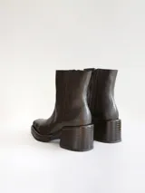 Bota corta de cuero negro con punta cuadrada y taco bloque texturizado. Presenta cierre lateral y costura central en el empeine.