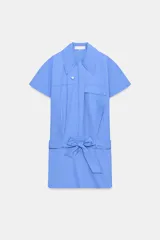 Vestido corto de estilo camisero color azul, con cuello solapa, manga corta y cierre frontal con botones. Presenta un bolsillo de plastrón con solapa en el pecho y un cinturón ajustable del mismo tejido en la cintura.