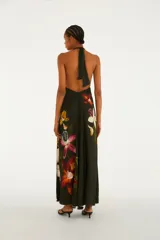 Mono palazzo largo de color negro con estampado de maxi orquídeas coloridas, escote en V pronunciado y tirantes halter que se atan al cuello. Presenta un diseño holgado y fluido.