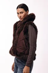 Chaleco acolchado color marrón con terminaciones de piel sintética en los bordes y cuello, aportando volumen y textura.