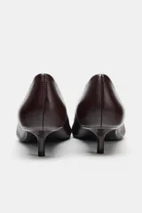Zapato de piel color marrón oscuro (casi negro), con punta fina y tacón bajo tipo kitten de 4 cm.