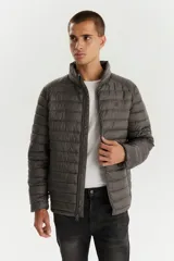Campera puffer de diseño acolchado, color gris oscuro, con cuello alto, cierre frontal completo y bolsillos laterales con cierre.