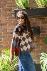 Sweater tejido de algodón con diseño de rombos multicolor en tonos marrones, azul y rojo. Presenta una silueta oversize, cuello redondo y mangas largas abullonadas con puños ajustados.