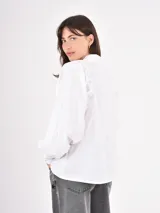 Camisa de manga larga en color celeste, con cuello clásico y cierre frontal de botones. Presenta un diseño con mangas abullonadas y puños ajustados.