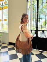 Cartera bandolera de cuero color camel con flecos largos en la parte inferior.
