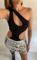 Body negro asimétrico de una sola manga, con aberturas en el pecho y la cintura.