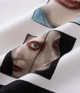 Remera blanca de algodón con modelado boxy, cuello redondo y manga corta. Presenta un estampado central en la parte delantera que forma una cruz con la palabra "MAYHEM" en el centro.