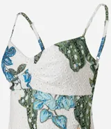 Vestido corto de corte evasé confeccionado en tejido laise con estampa tropical de flores azules y hojas verdes. Presenta escote en V, breteles finos ajustables y diseño con perforaciones caladas características del broderie.