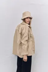 Camisa de pana color beige, con corte oversize, cuello clásico, bolsillos frontales y cierre con botones.