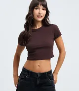 Blusa cropped de manga corta y cuello redondo, confeccionada en tejido de algodón con elastano. Presenta un diseño ajustado al cuerpo en color marrón.