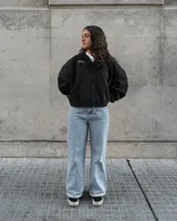 Canguro negro con capucha y cierre frontal, con texto bordado en el pecho y bolsillos laterales.