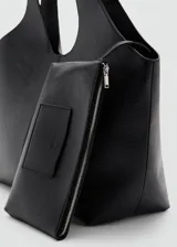 Bolso tipo hobo color negro, confeccionado en poliuretano con textura granulada, asa de hombro integrada y diseño amplio y flexible.
