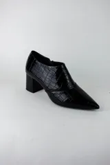 Botines de caña baja con acabado acharolado y textura efecto cocodrilo. Presentan punta fina, cierre lateral y taco cuadrado de altura media.