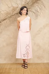 Conjunto negro de dos piezas de lino, compuesto por un top de un hombro con bordados florales y una falda midi con aberturas laterales y bordados florales.