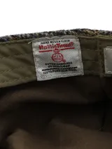 Boina de lana Harris Tweed con patrón de cuadros en tonos marrón y gris, forro interior y diseño clásico.