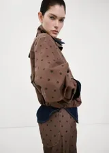 Chaqueta bomber de algodón color marrón con estampado de lunares, cuello embudo, manga larga, bolsillos laterales y cierre oculto con cremallera y botones a presión.