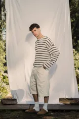 Sweater de tejido ligero a rayas horizontales blancas y negras, con cuello redondo y mangas largas. Presenta un pequeño bordado en la manga.