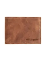 Billetera de cuero marrón de la marca Hush Puppies, diseño plegable con costuras pespuntadas en los bordes y logotipo grabado en relieve en la esquina inferior derecha.