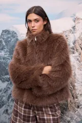 Chaqueta de pelo sintético color marrón chocolate, con cuello alto y cierre frontal mediante cremallera.