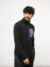 Buzo de entrenamiento Umbro con medio cierre frontal, cuello alto y bolsillo en el pecho de nylon con cierre. Presenta una textura sutil en el tejido y logo de la marca estampado en el bolsillo.