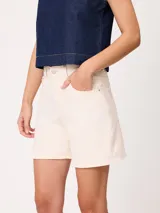 Short de denim elastizado de tiro alto, color beige, con bolsillos delanteros y traseros, y cierre frontal con botón y cremallera.