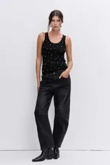 Blusa de punto sin mangas, color negro, con escote redondo y detalle de pequeñas tachas metálicas plateadas distribuidas por toda la prenda.