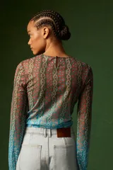 Top de mangas largas con estampado floral en tonos azules, verdes y naranjas. Tiene un cordón ajustable en el centro que crea un efecto drapeado.