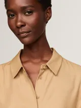 Camisa color beige de viscosa, de corte amplio, con cuello inglés, cierre frontal con botones y logo metálico de Tommy Hilfiger en la manga.