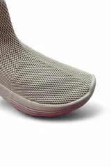 Bota tipo zapatilla de caña alta confeccionada en tejido de malla y material sintético, color beige, con suela robusta y diseño tipo slip-on.