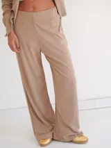 Pantalón de tiro medio con silueta recta y leve amplitud, confeccionado en tejido suave de caída fluida y cintura limpia sin cierre visible.