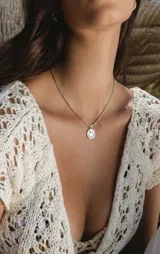Collar de acero con cadena fina y dije redondo con relieve de cara feliz sonriente.