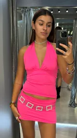 Minifalda de tiro bajo color fucsia neón, confeccionada en tela elástica, con detalle de cinturón de cadena con eslabones cuadrados de strass.