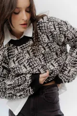 Buzo de tejido grueso con diseño artesanal bicolor en tonos marrón y crema. Presenta cuello redondo y terminaciones en rib en puños y cintura, con un calce relajado.