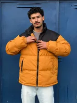 Campera puffer color mostaza con cuello alto y cierre frontal con cremallera.