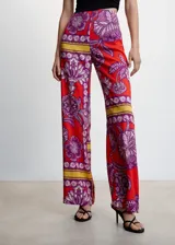 Pantalon palazzo de tiro alto con estampado floral y geométrico en tonos rojos, violetas y amarillos. Confeccionado en tejido fluido con cierre lateral de cremallera.