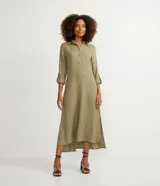 Vestido chemise largo color naranja, confeccionado en viscolino. Tiene cuello solapa, cierre con botones, manga larga con martingale, aberturas laterales y no tiene estampado.